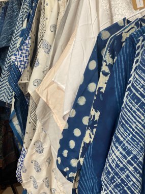 Closeup of various patterned indigo printed silk garments hanging on a rack