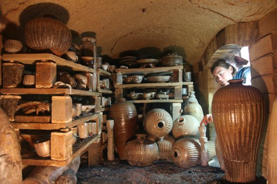 person peaking inside a kiln with recently fired ceramic wares