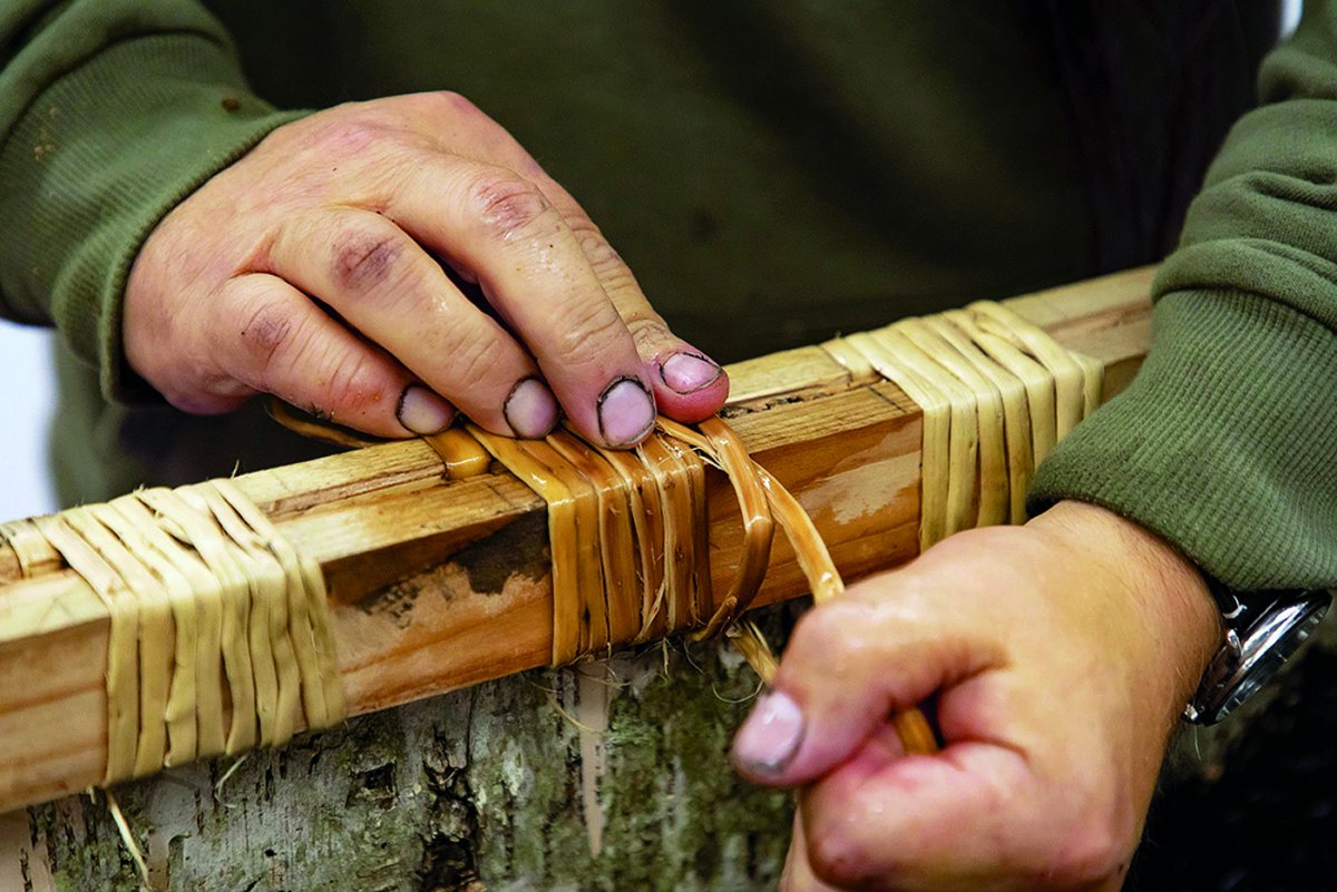 A set of hands doing detail work on canoe wood.