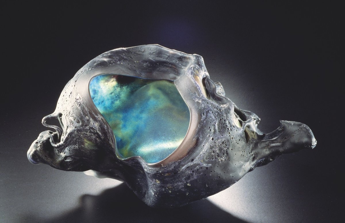Iridescent tektite stone creating a seashell like sculpture.