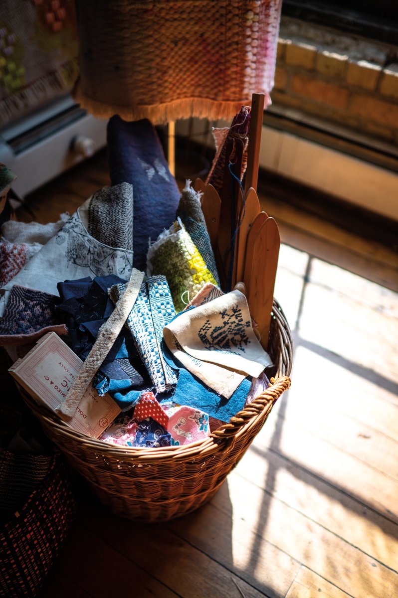 A basket full of weaving tools, embroideries, quilt squares, and handwoven cloth waits to be incorporated into future textile artworks.