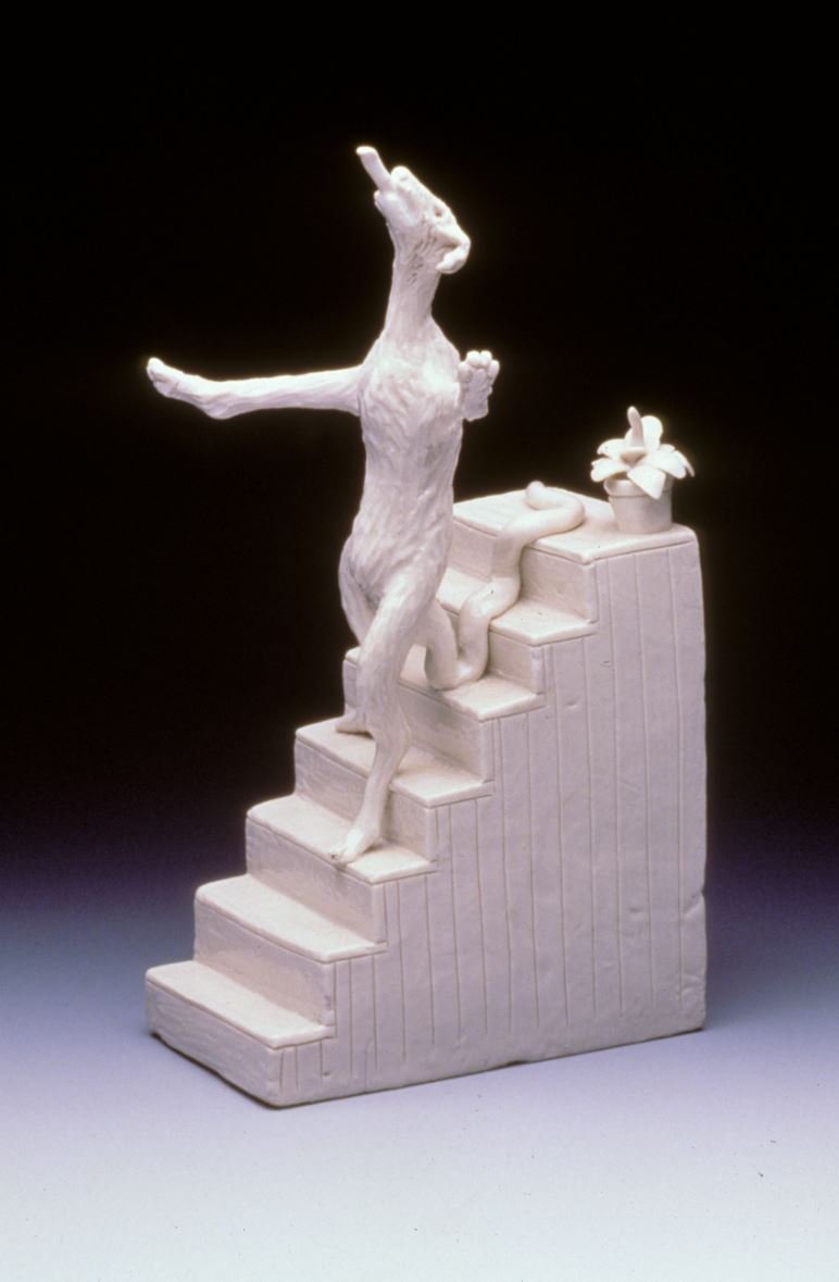 Ceramic sculpture of dog descending a staircase on two legs like a human.