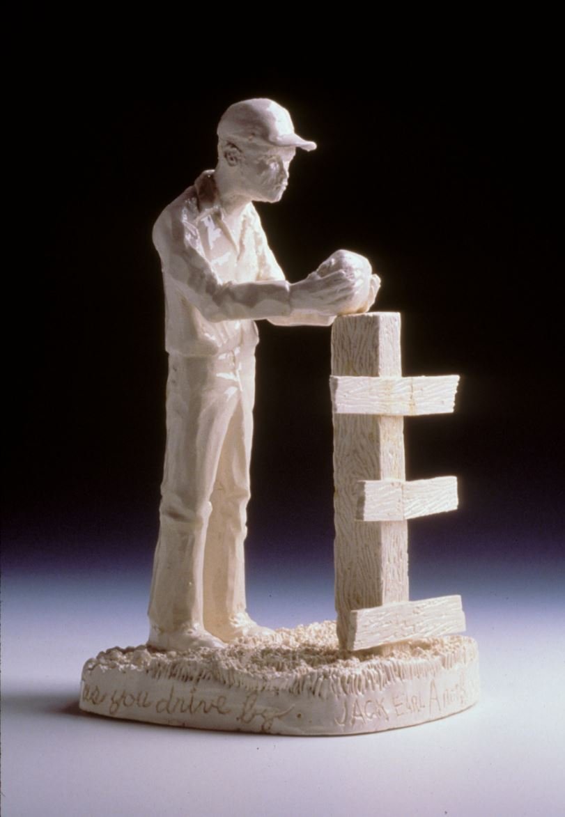 Ceramic sculpture of a man placing a rock on a fencepost.