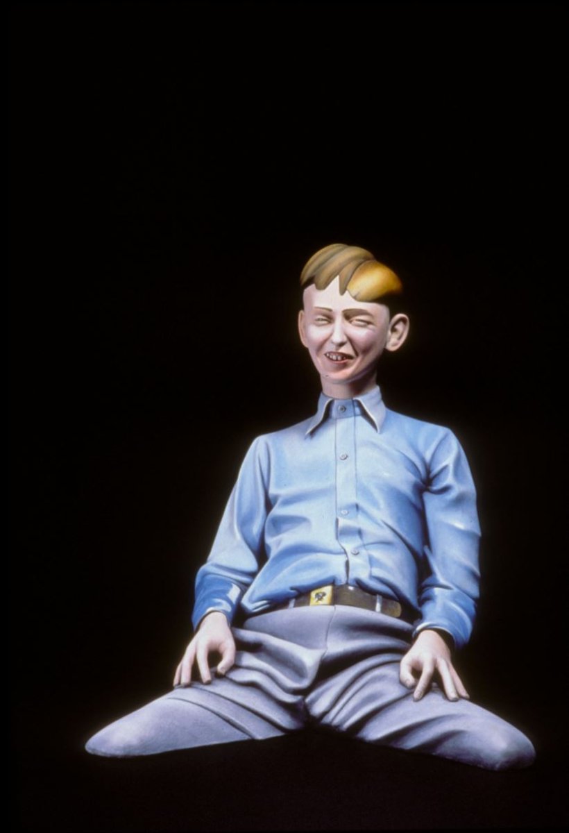 Three-quarter bust of a seated man dressed in all blue with a grin.