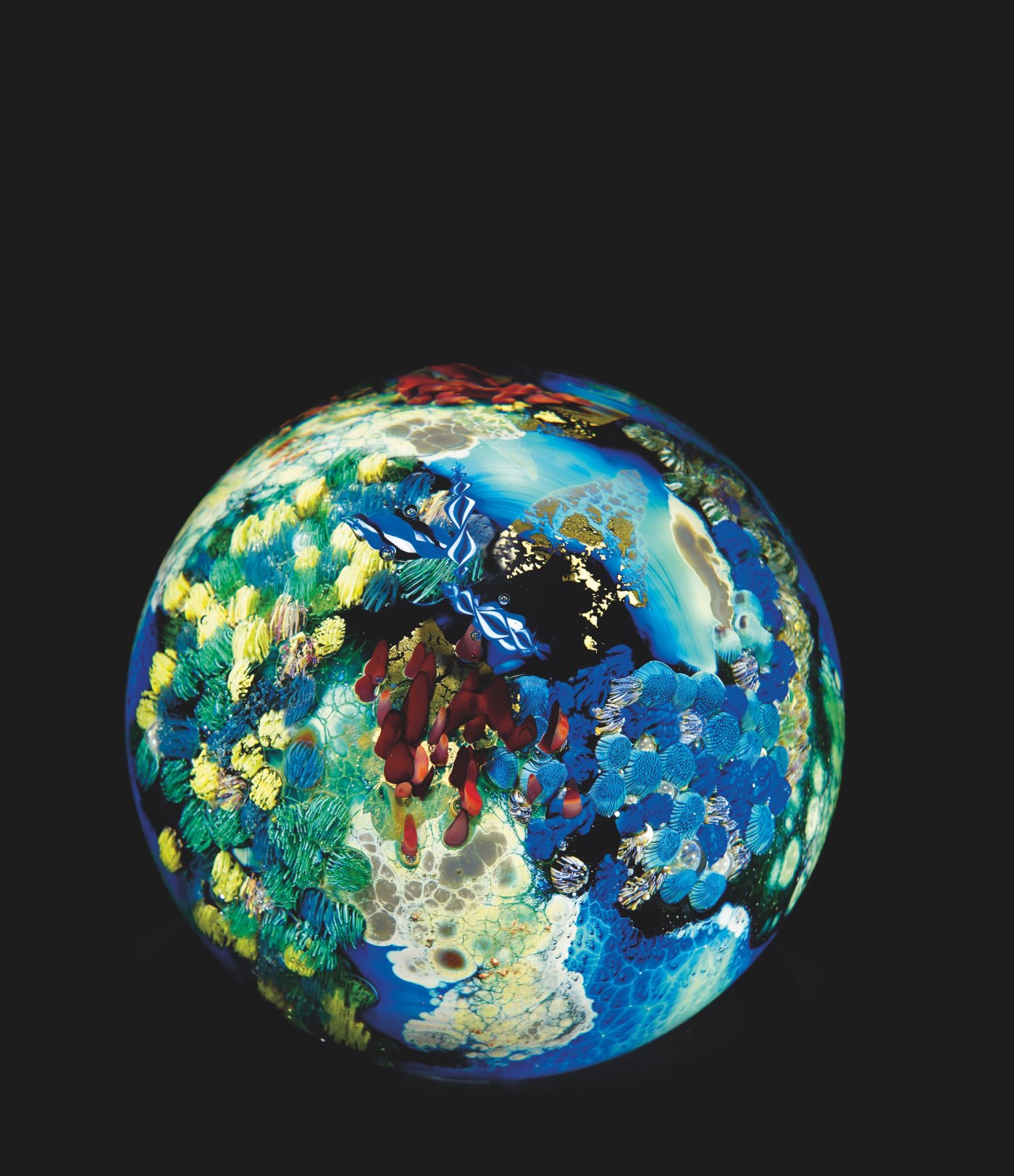 Glass sphere with blues, greens, yellows, reds and gold shapes creating a planet-like image, 5.25 in. diameter