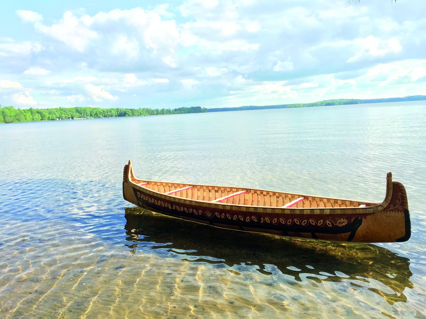 Handmade canoe sitting in large body of water. 