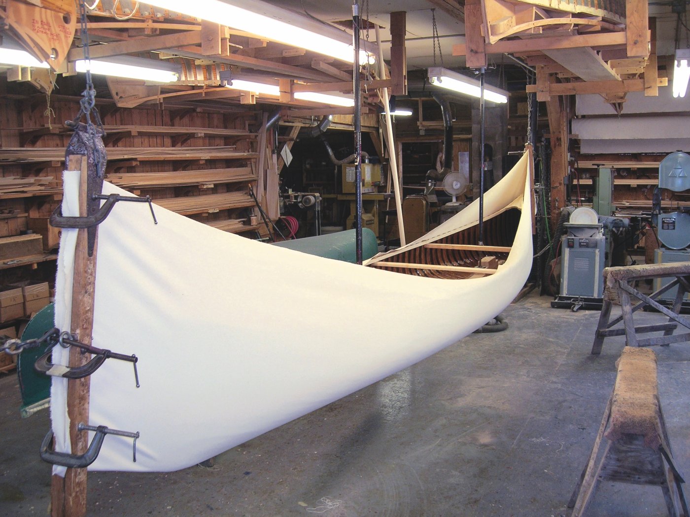 The wooden hull of a canoe being inserted into a canvas envelope.