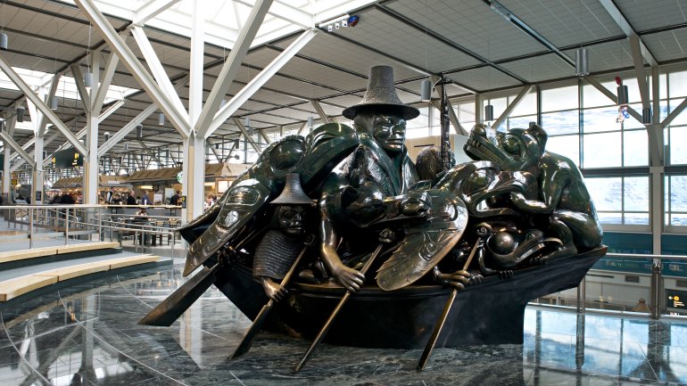 bronze sculpture shown in an airport terminal depicting figures and animals in a boat with oars