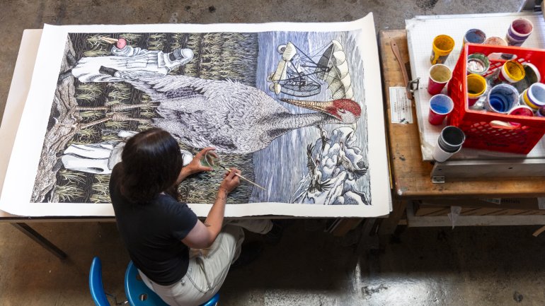 Pippin Frisbie-Calder applies watercolor to her 2017 woodcut Contemporary Heroes, which references Operation Migration and supports conservation groups, 69 x 39 in. Photo by Cedric Angeles.