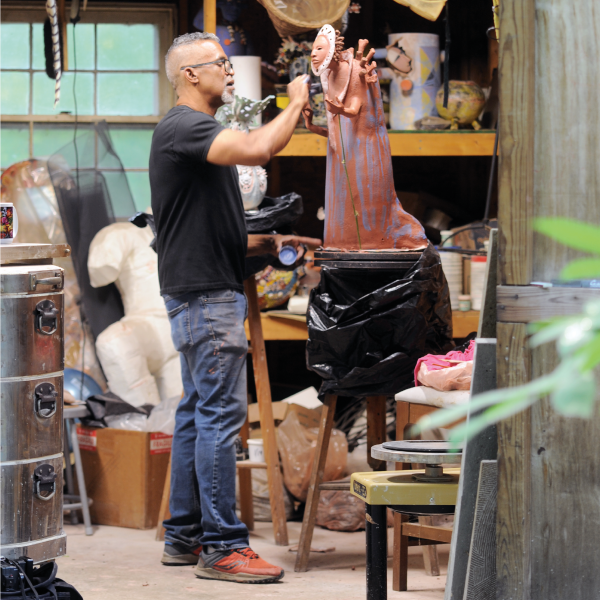 Malone sculpting in his kiln shed and creative space. Photo by Steven M. Cummings.
