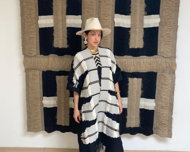 textile artist rhiannon griego posing in front of tan and black handwoven textile artwork