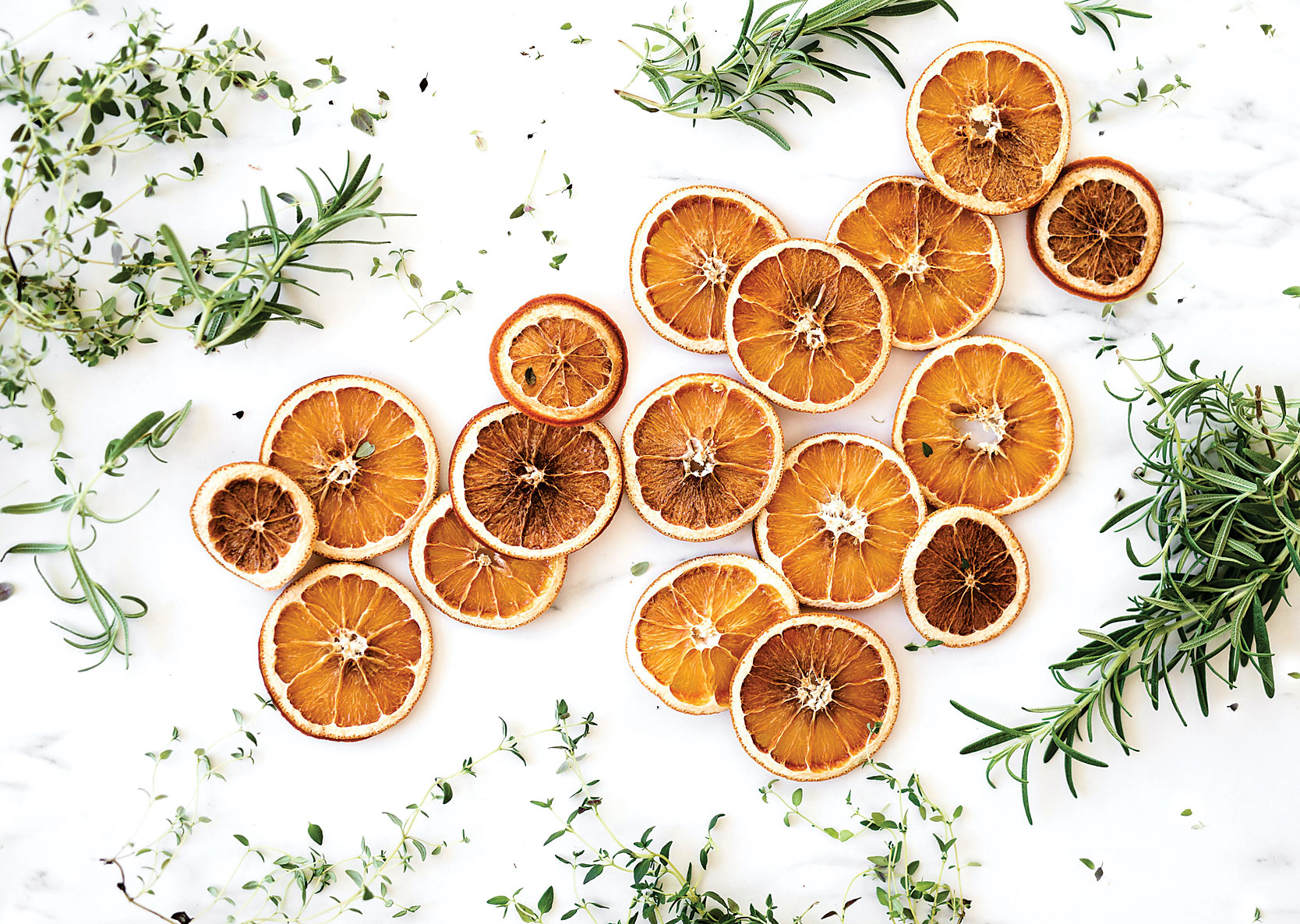 Dried orange slices and herbs spread on marble