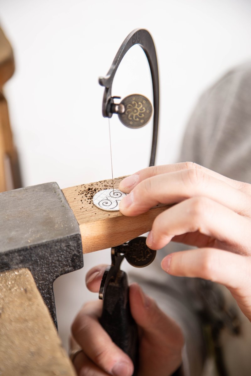 The artist cuts metal pieces for jewelry. Photo by Dina Kantor.