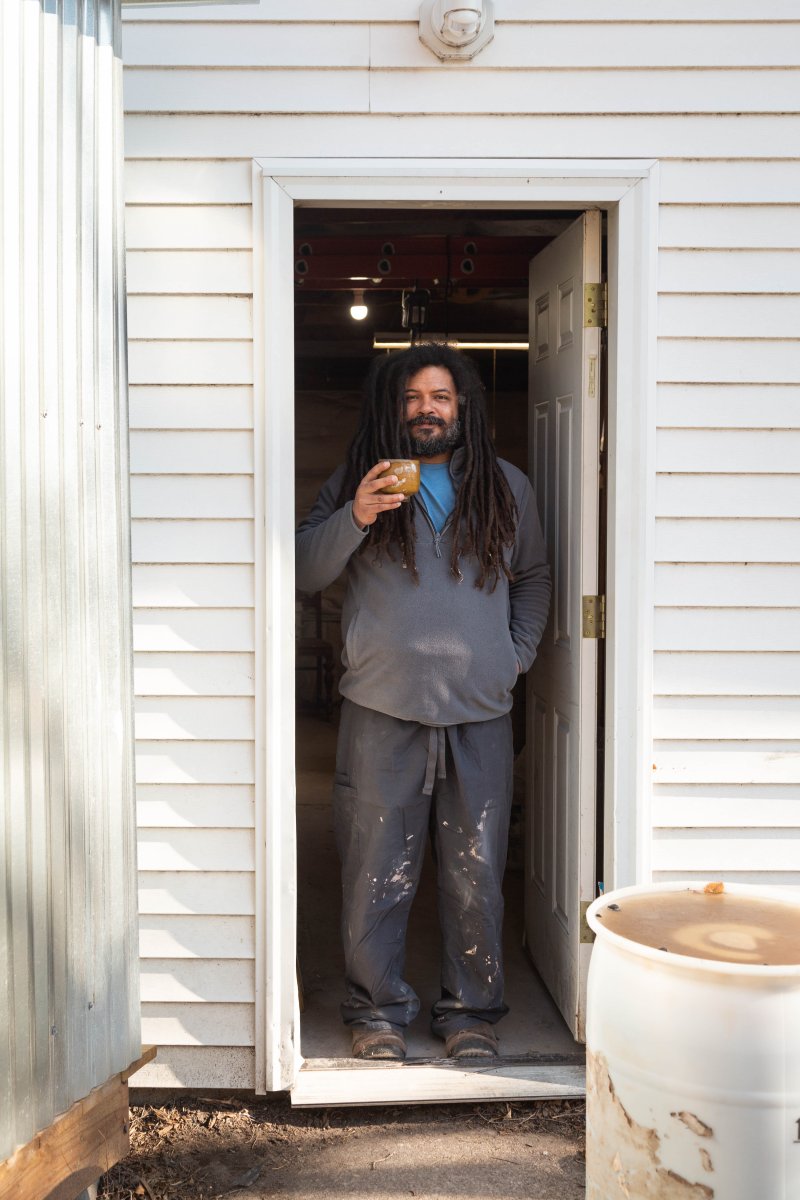 Venzant in the doorway to his studio holding one of his cups. Photo by Dina Kantor.