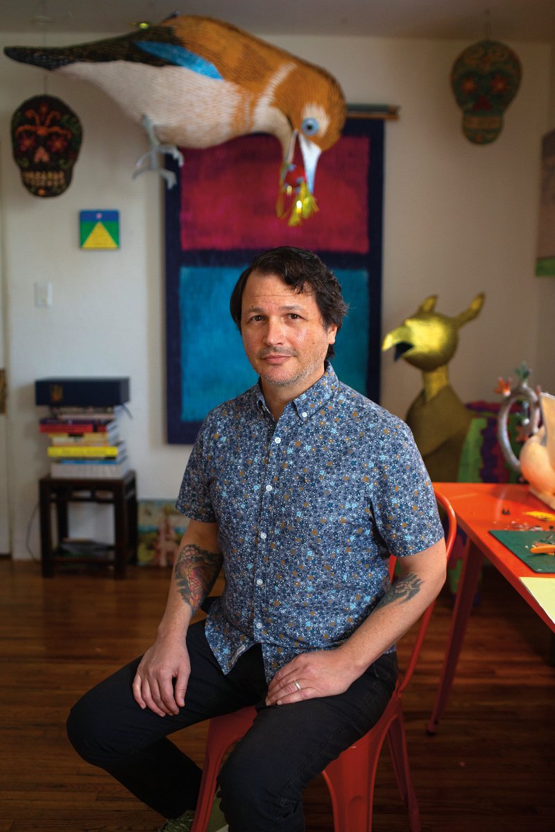 The artist in his studio surrounded by completed works, including Sugar Skull Piñata No.1, 2009, his very first piñata sculpture, which hangs just below the tail of one of his Bosch birds. Photos by James Bernal.