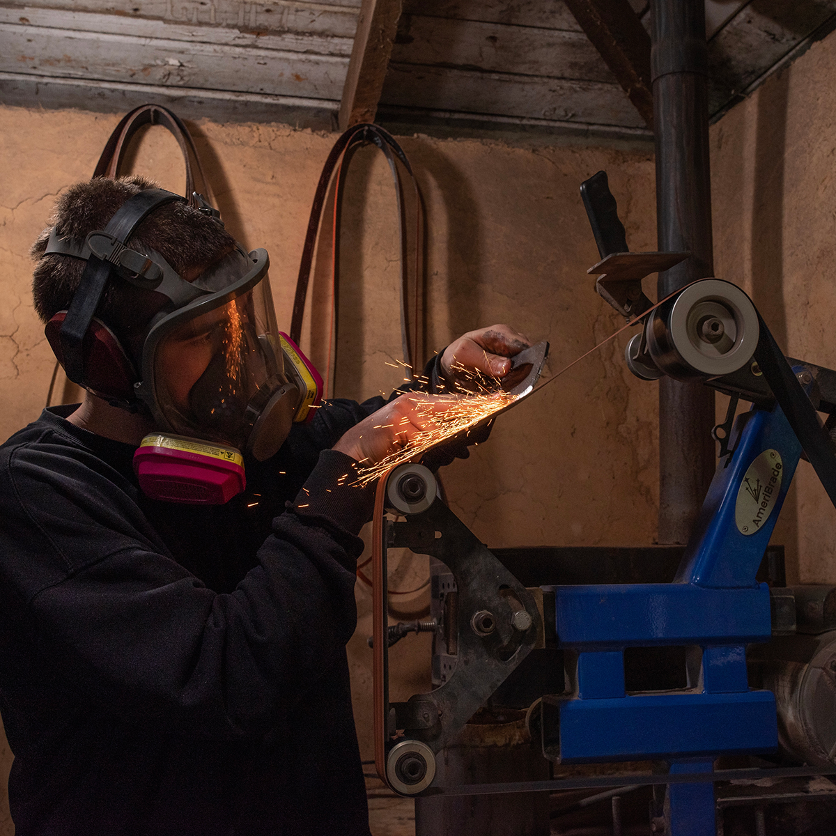 Noel grinds a knife in his studio. Photo by Kian Berreman.