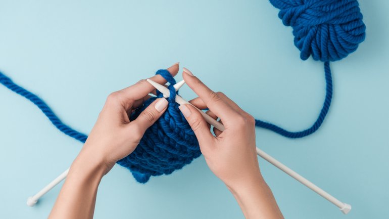 Hands knitting blue yarn