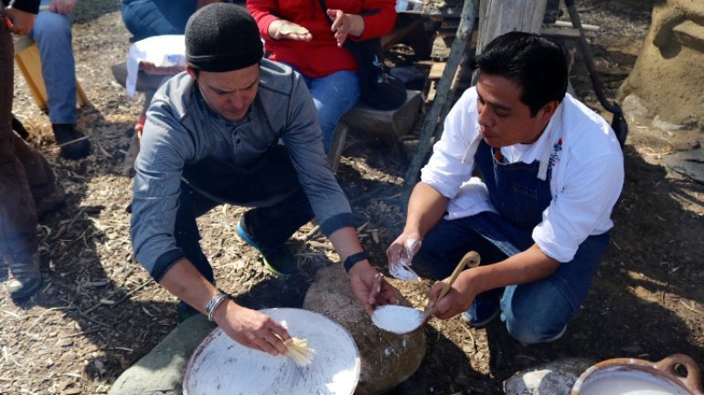 Neftali Duran instructing someone on cooking with a clay comal