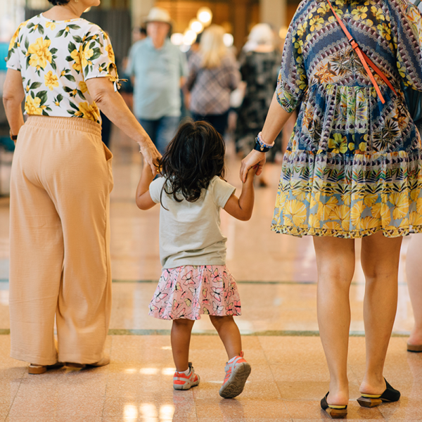 Child holding hands with adults at arts event