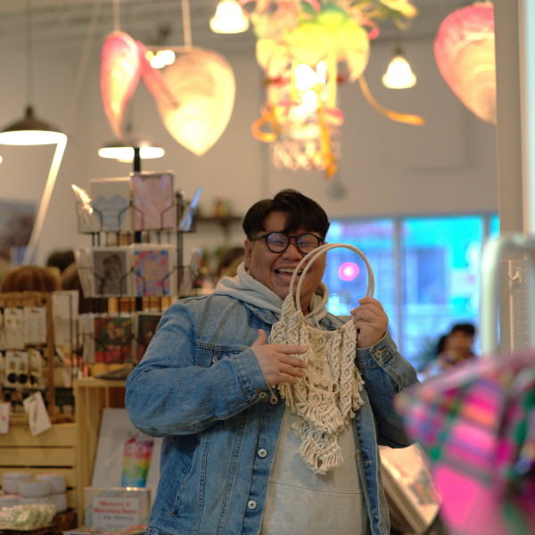 A guest at XIA Gallery & Cafe enjoys a macrame hanger made by Na Vang, owner of Macradolls. The hanger is Vang's take on the xauv traditional Hmong necklace. Photo by Leanghout Prom.