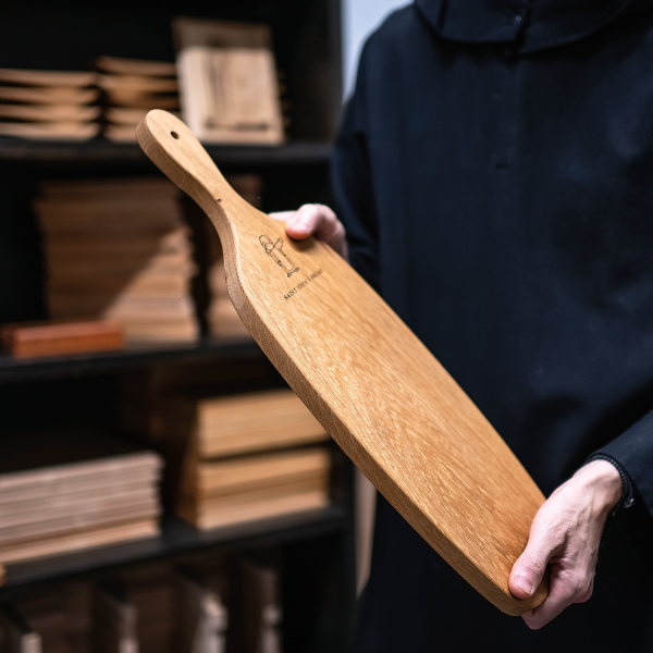 Grobe holds a bread paddle made of wood harvested from the Abbey Arboretum.