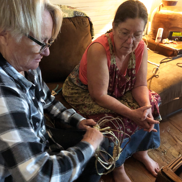 Sophocles (left) concentrates on learning a basketry technique while Basket watches, waiting to help if needed. 