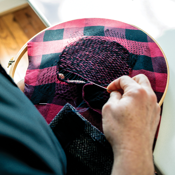 Newport makes fine stitches using an embroidery hoop. Photo by Darrel Ellis.