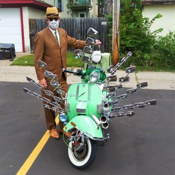 Portrait of kent aldrich wearing mask hat sunglasses and brown suit posing with decked out moped