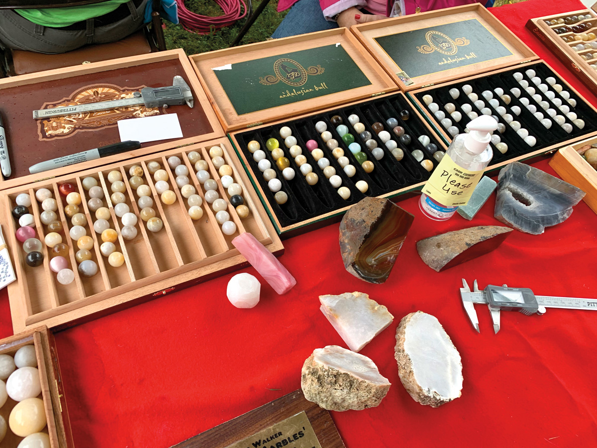 A display of handcrafted marbles and the stones and tools used to make them.