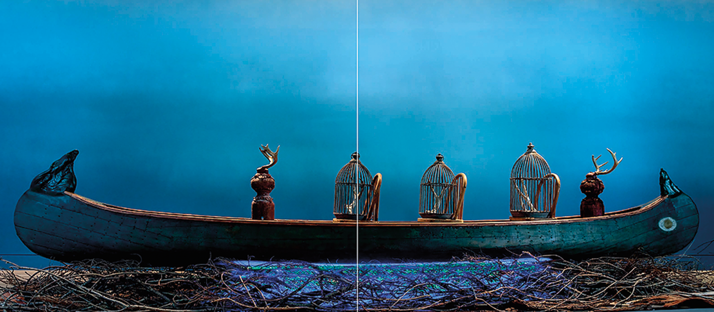 A canoe bearing birdcages on wooden chairs and idols with horns on a spiritual journey through a blue night-scape