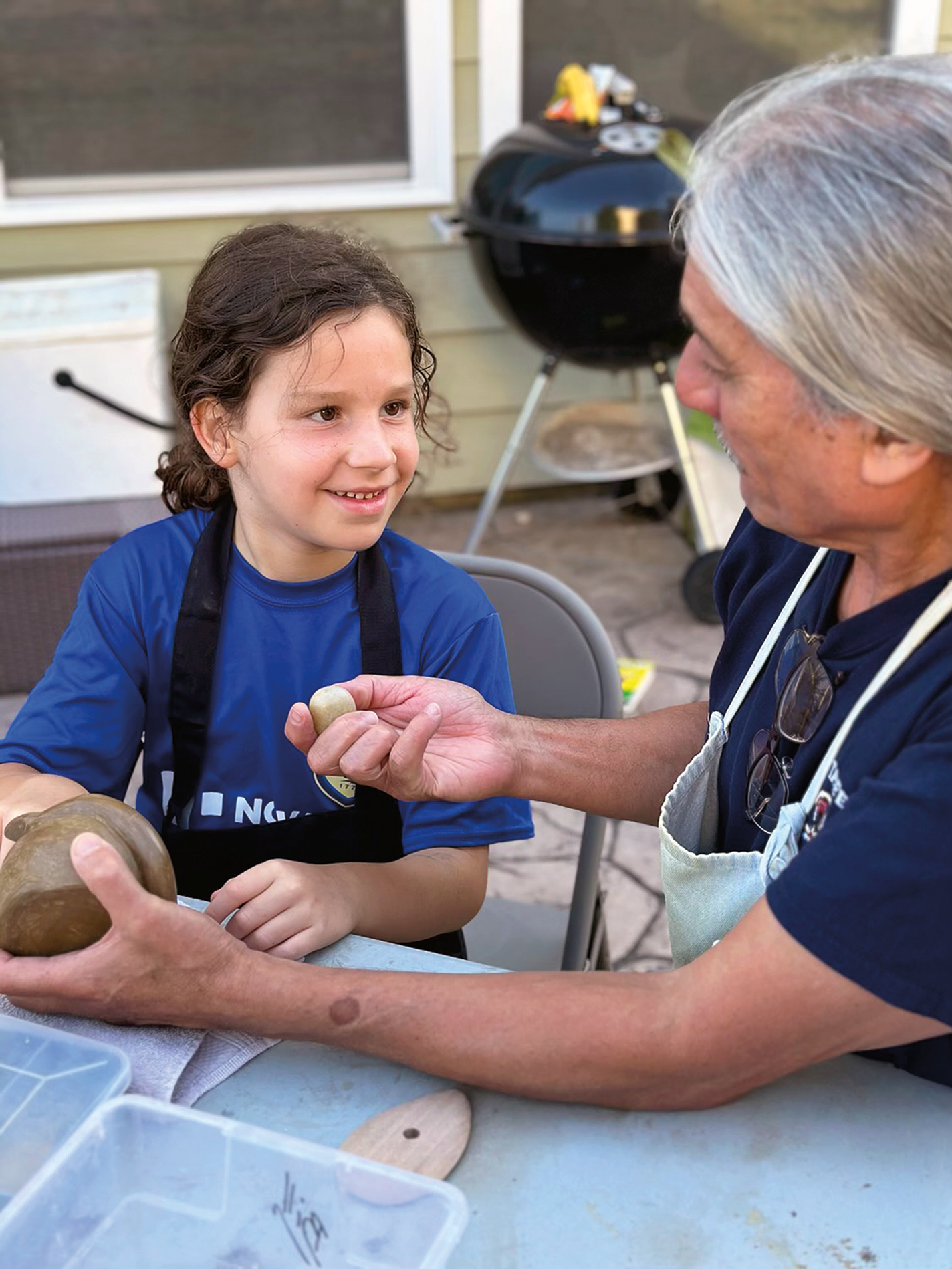 Harris teaches pottery techniques to a child