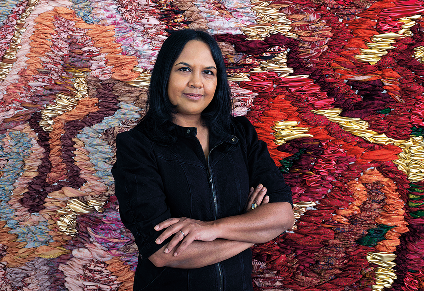 Artist Suchitra Mattai stands in front of one of her tapestries.