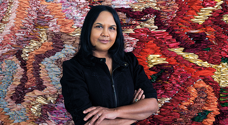 Artist Suchitra Mattai stands in front of one of her tapestries.