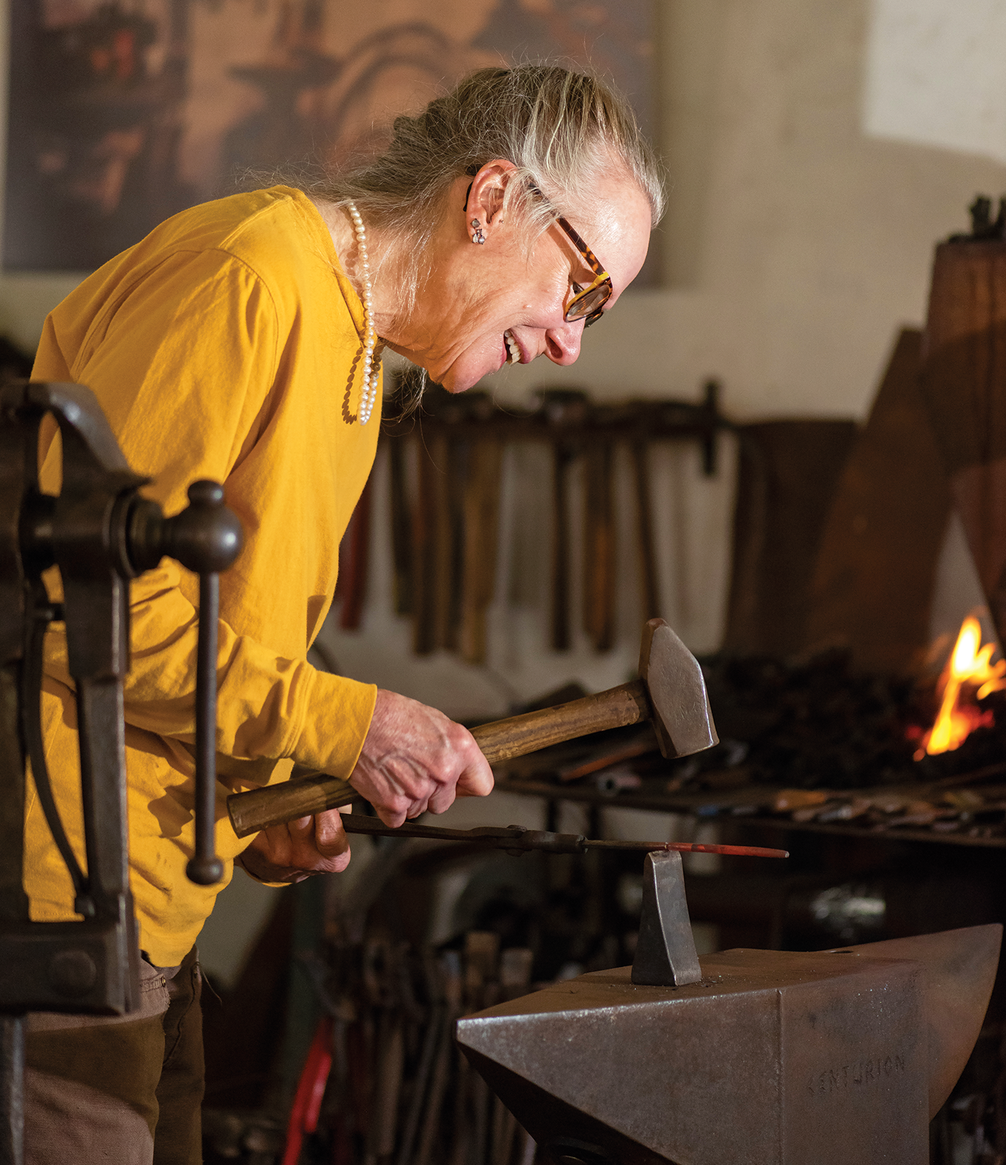Elizabeth Brim uses a tool called a hardy to cut a piece of red-hot metal in two.