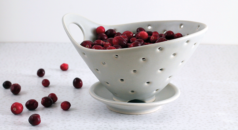 Small porcelain berry bowl with a handle and holes for rinsing
