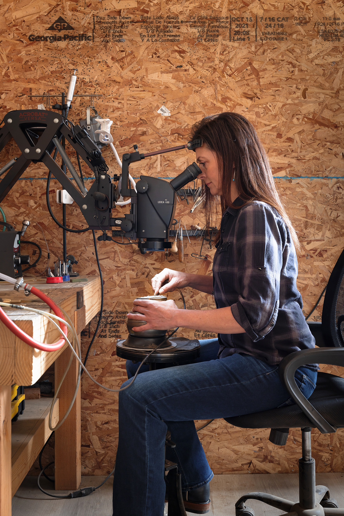 Amy Erickson in her shop, looking through a microscope while engraving.