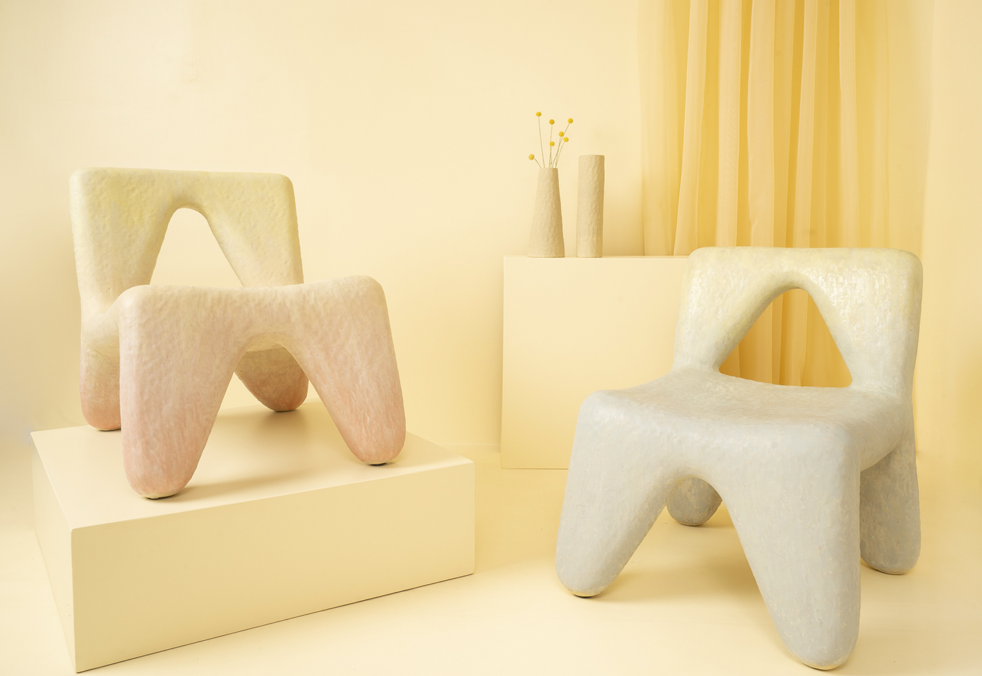 Two soft-looking ceramic chairs with textured surfaces in faded colors.