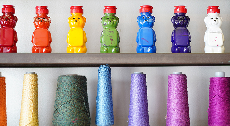 Honey bears filled with paint populate a supply shelf.