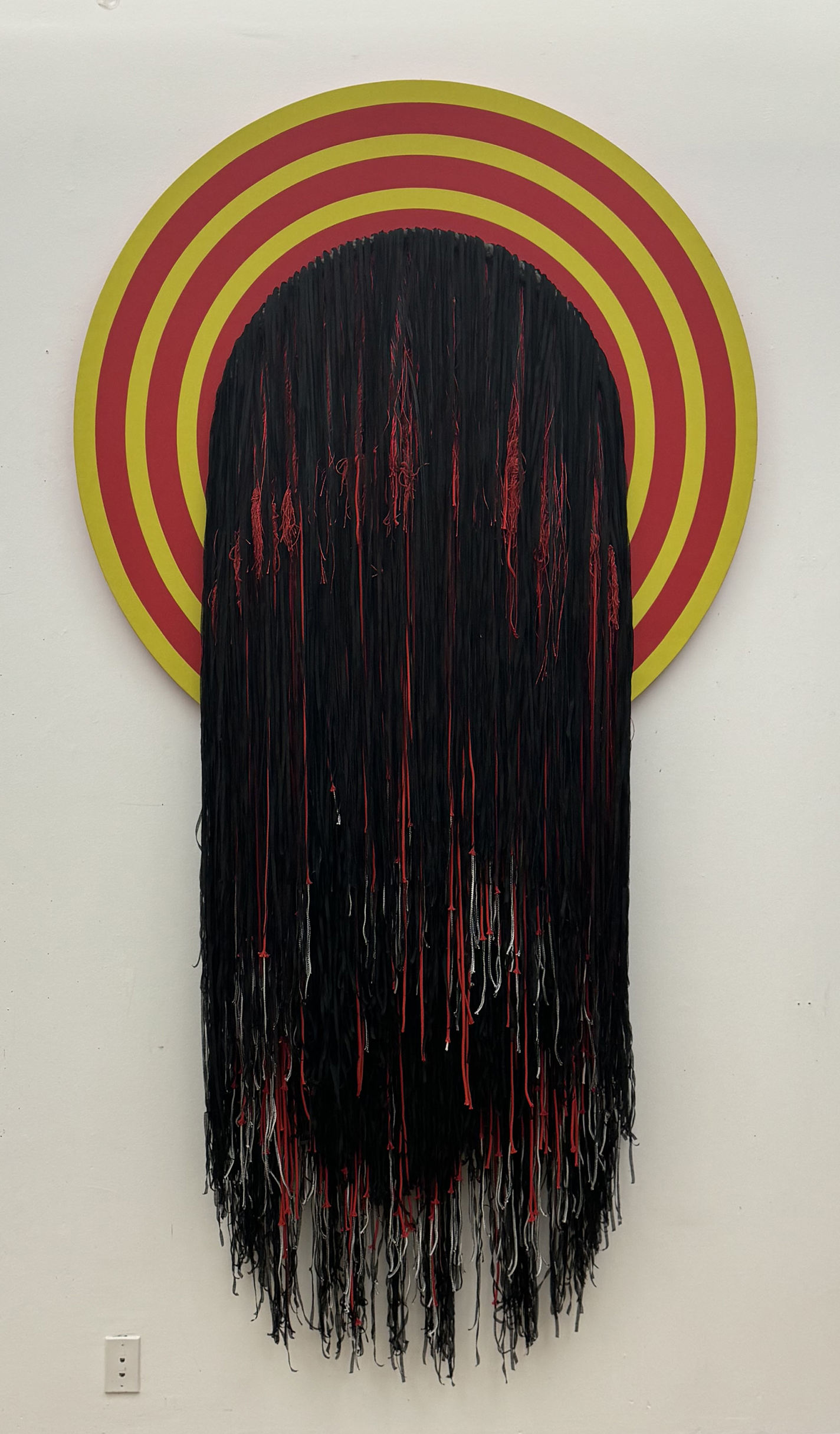 Textile sculpture mounted on gallery wall.