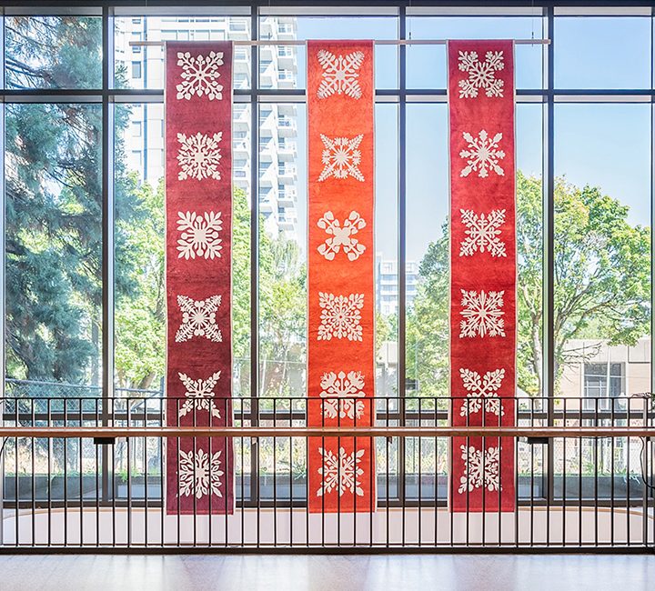 An installation of three kapa banners in front of a large window.