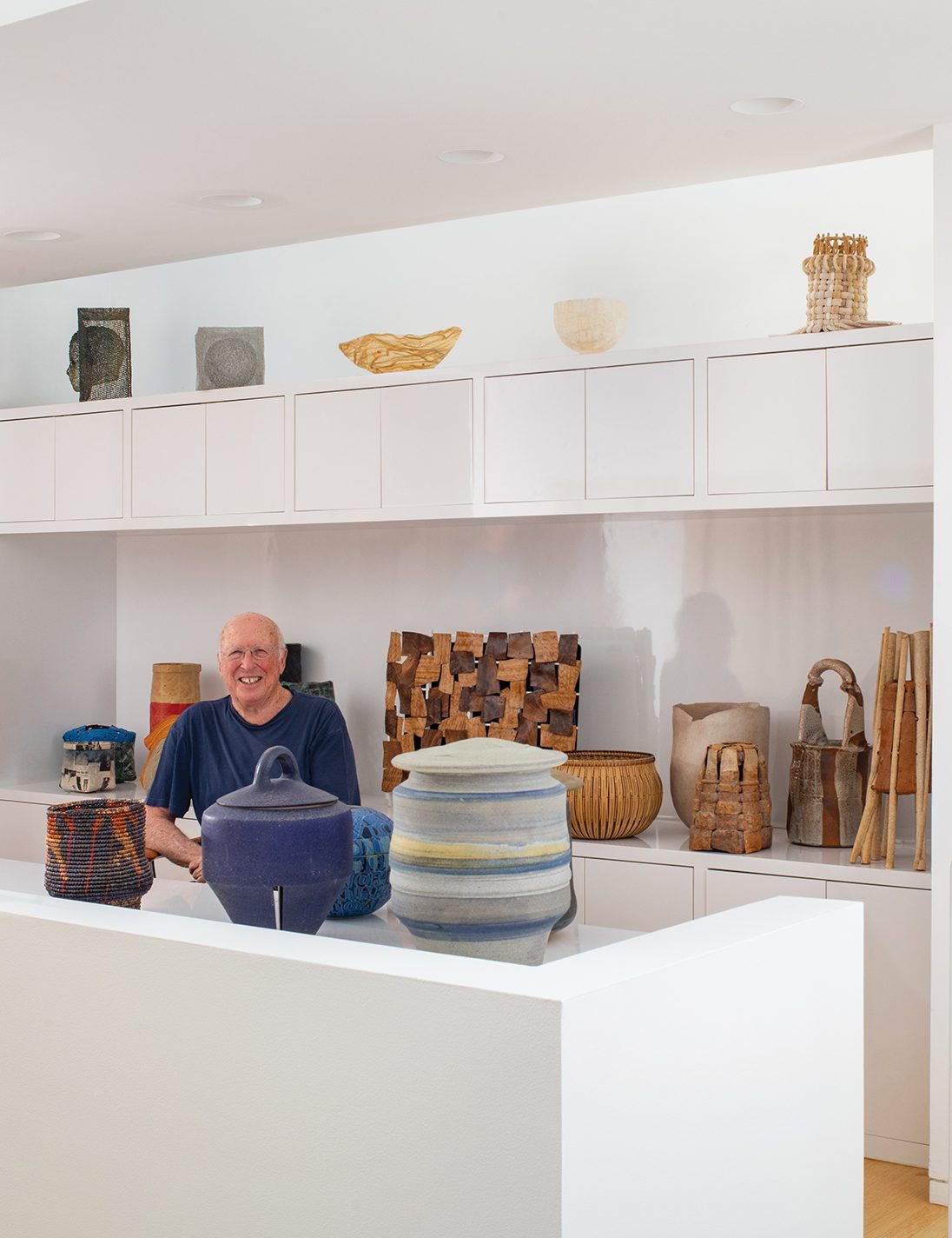 Lou Grotta poses with a variety of pots, baskets, and sculptures.