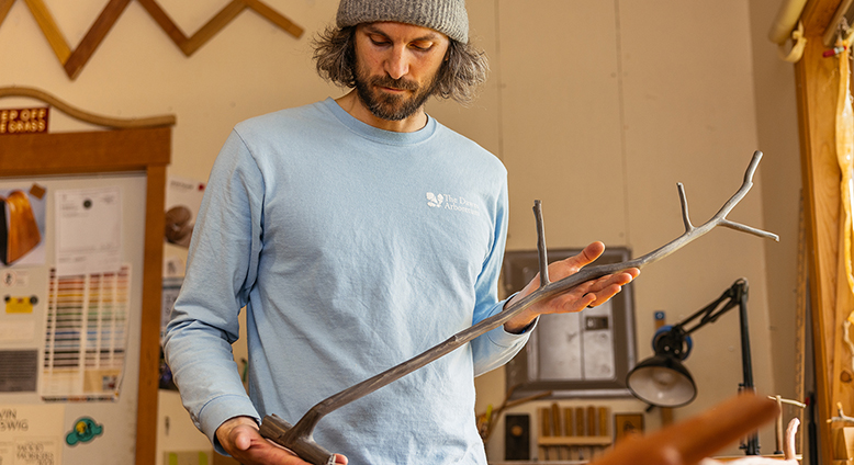 Kevin Reiswig holds a tree branch-shaped sculpture crafted from reclaimed wood at his studio in Port Townsend, Washington.