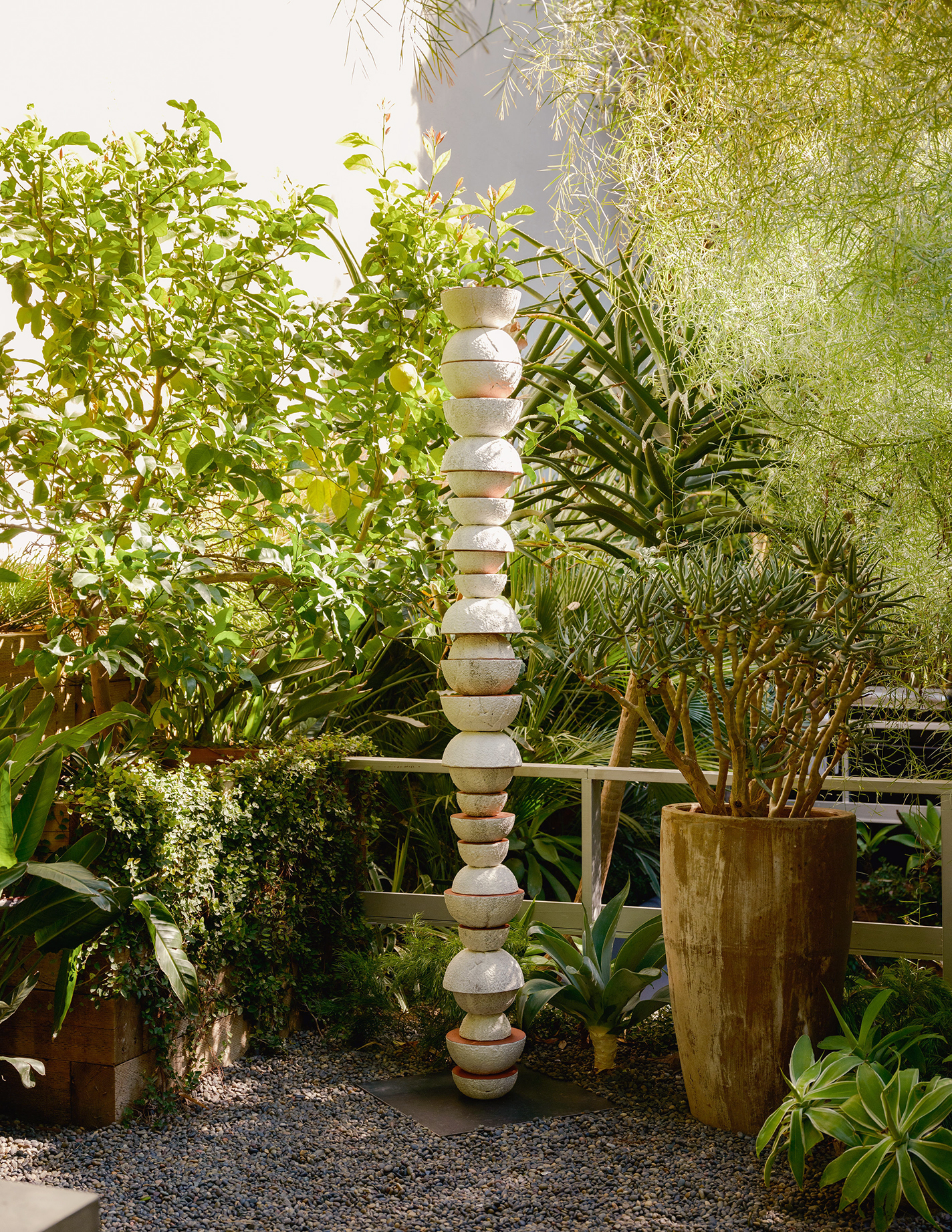 Stacked terra-cotta sculpture in garden.