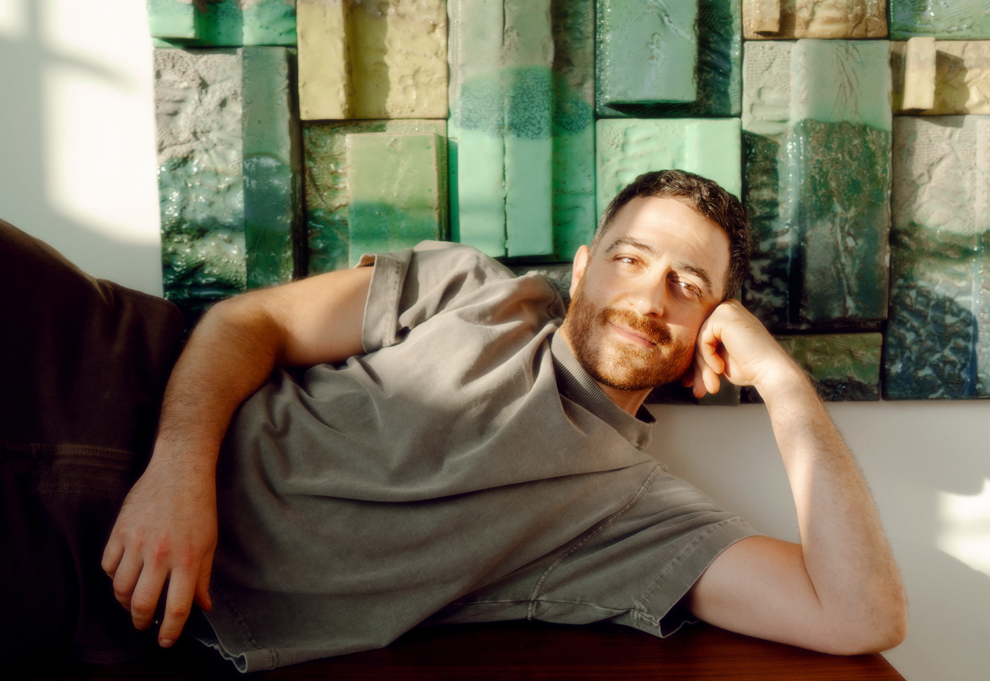 Ben Medansky poses in front of a ceramic tile-clad wall.