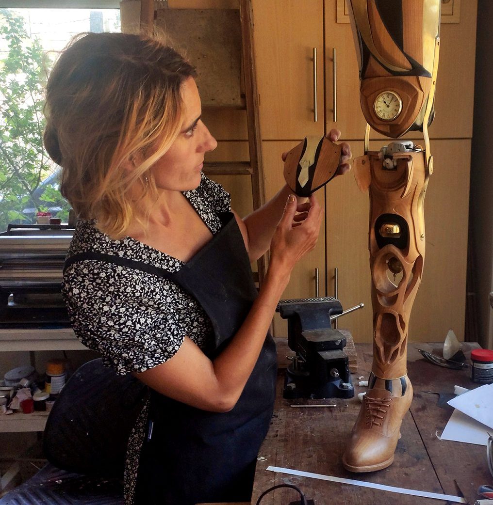 De Oliveira Barata assembles parts of a prosthetic leg made from carved wood with a working cuckoo clock.