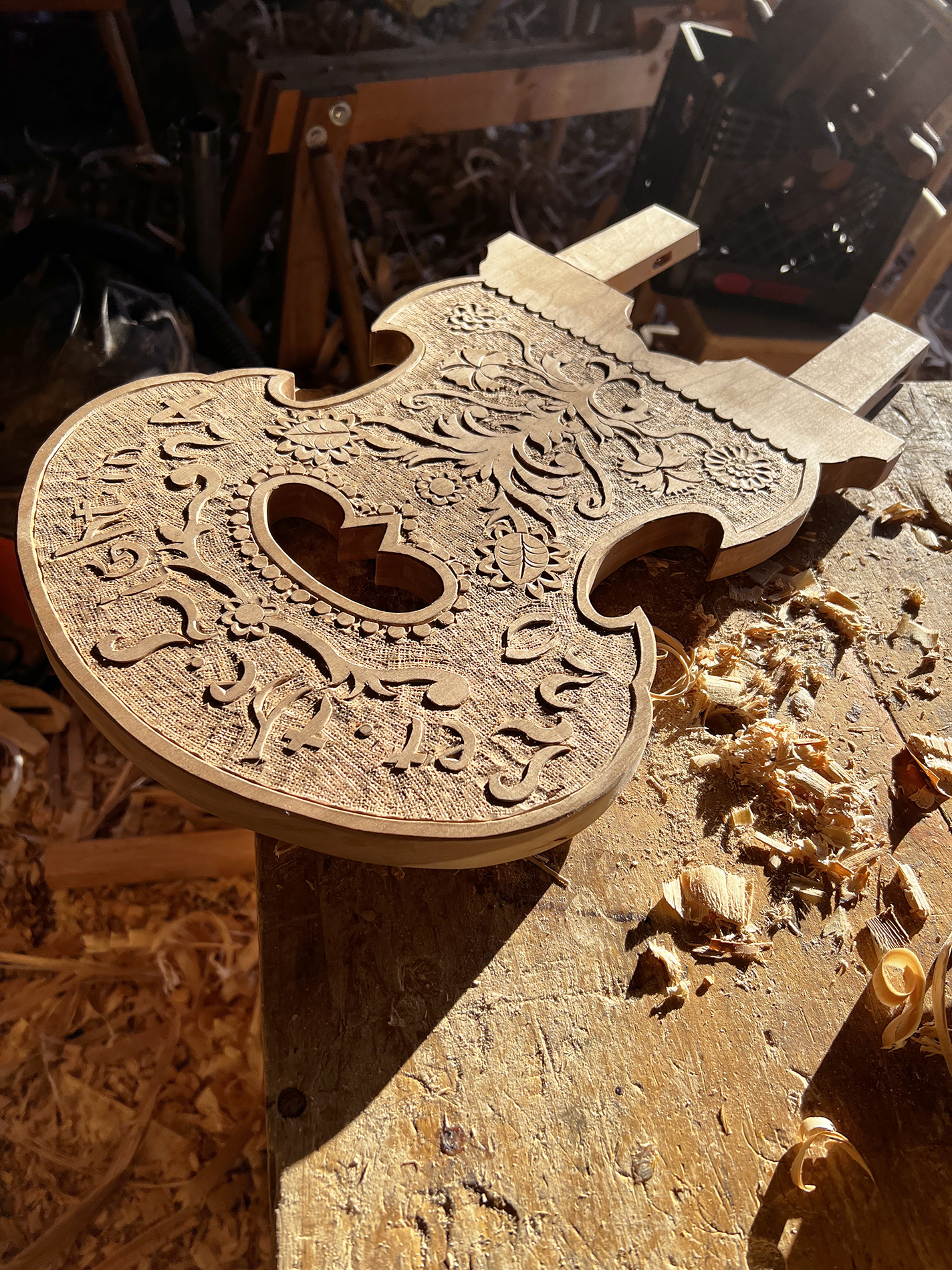 An in-progress brettstuhl in cherry, hickory, and ash reads “Let the Light In,” an homage to a song by Lana Del Rey.