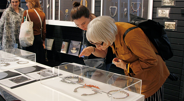 Visitors look at jewelry in an exhibition.