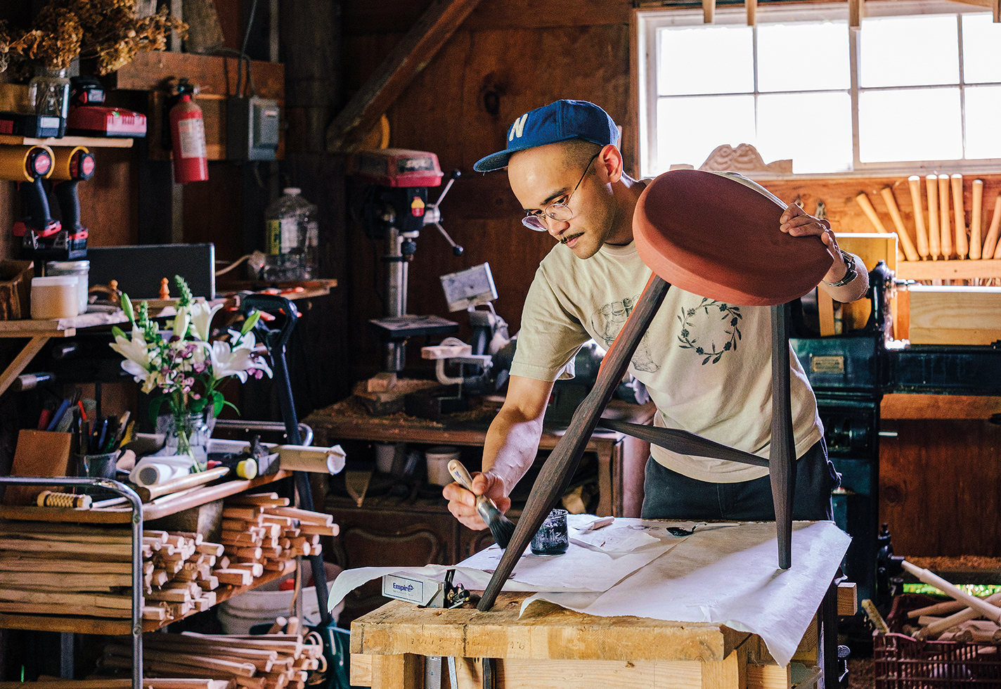 Charles Thompson applies paint to a wooden stool.