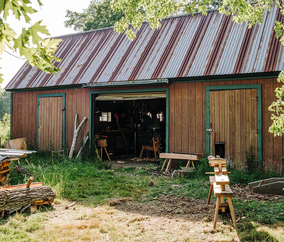 A red oak log and shave horse in front of the studio.