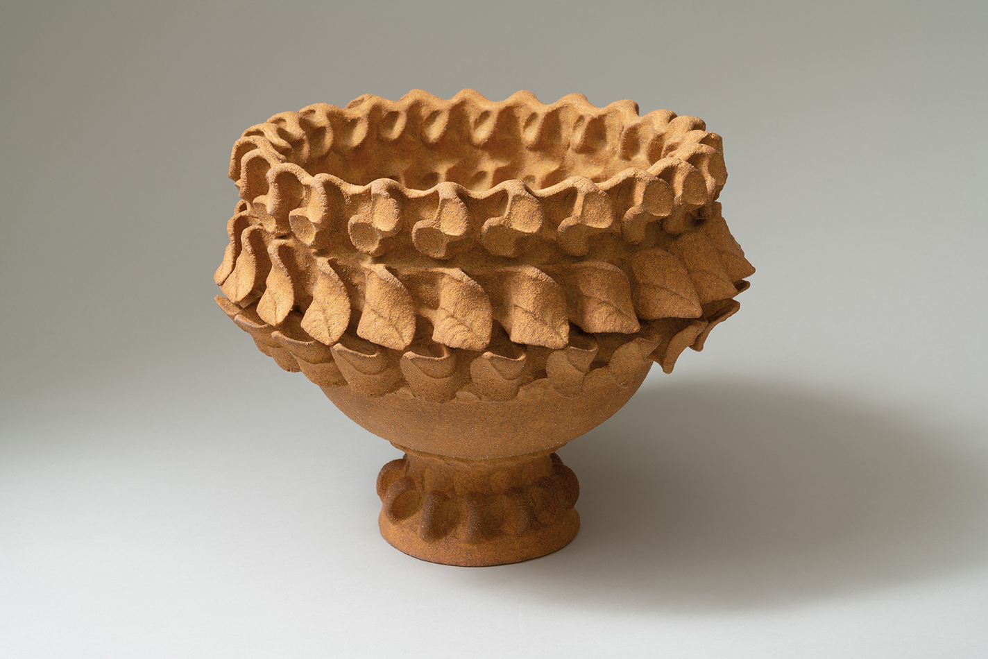 Unglazed ceramic vase with intricate leaf shapes